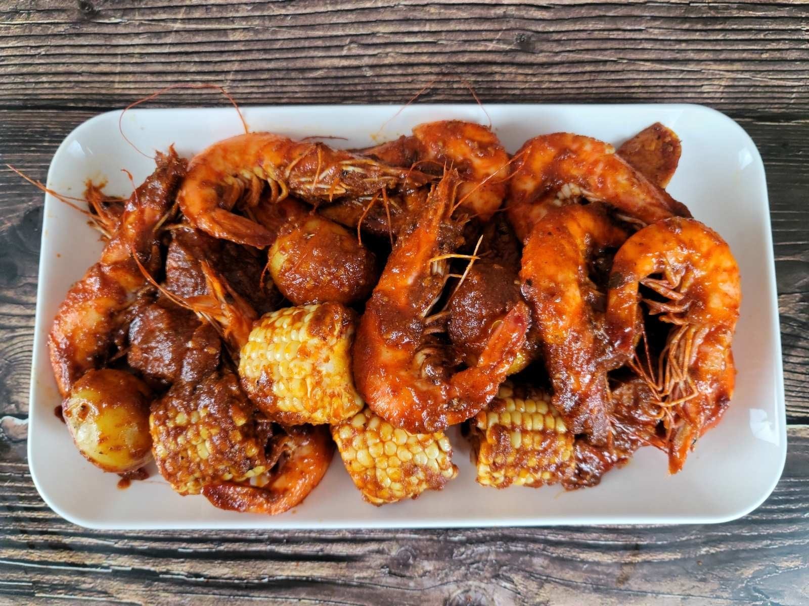 Overhead spread of sauced shrimp, crawfish, corn and potatoes